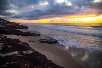 Spectacular orange cloudy sunrise over the pacific ocean at wild ten mile beach. Black rocks campsite, NSW, Australia