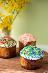Easter composition with Easter cakes, wooden stand and spring flowers on a yellow background. copy space
