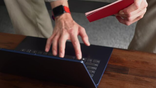 Closeup view of male hands typing on keyboard of laptop his personal information from passport. Man is inputting name and surname in identification base on computer. Concept of working distantly