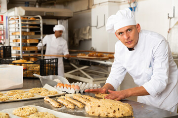 portrait male baker making cookies in bakehouse