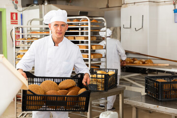 male baker with sesame bread in green box in kitchen