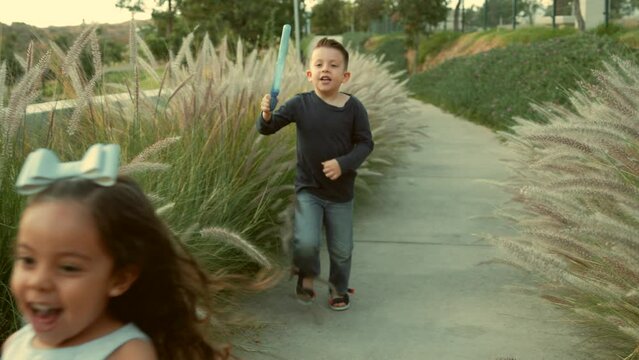 Ni&ntilde;o guapo rubio latino jugando a soplar y hacer burbujas caminando divertido disfrutando de una caminata y de un hermoso d&iacute;a soleado en el parque al aire libre al atardecer
