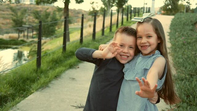ni&ntilde;os hermanos amigos primos felices disfrutando de su amistad jugando riendo en el parque saludando al aire libre en un hermoso atardecer en un d&iacute;a soleado muy juguetones y felices