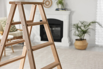 Wooden folding ladder in stylish living room. Space for text