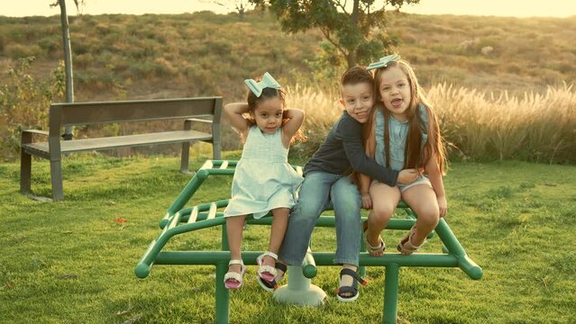 Ni&ntilde;os hermanos amigos primos tiernos y amorosos jugando y disfrutando riendo divertidos y sonrientes en un hermoso d&iacute;a soleado al atardecer al aire libre en el parque