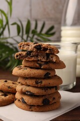 Stack of delicious chocolate chip cookies and milk on wooden table