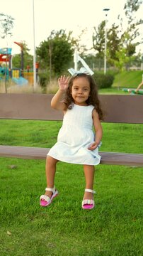 Ni&ntilde;a peque&ntilde;a chiquita bebe hermosa latina sonriente tierna amorosa jugando disfrutando y saludando a la c&aacute;mara sentada en una banca divertida en un hermoso d&iacute;a soleado al atardecer en el parque