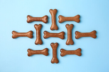Bone shaped dog cookies on light blue background, flat lay