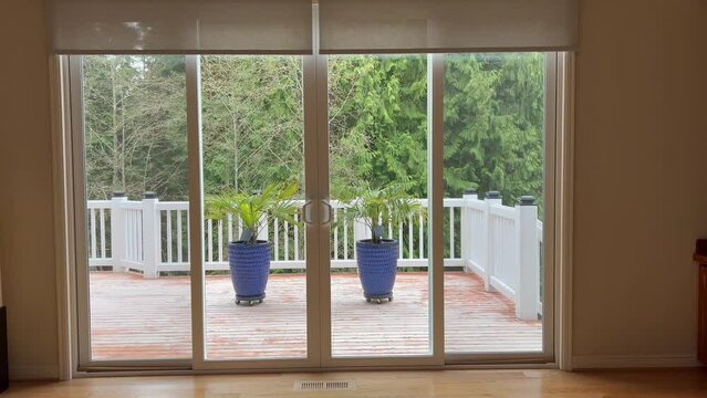 4K video of motorized roller shades in home living room interior being lowered. Automatic beige color roller shades are battery powered via remote or smartphone control