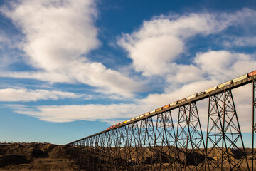 Train crossing a large metal bridge with clouds