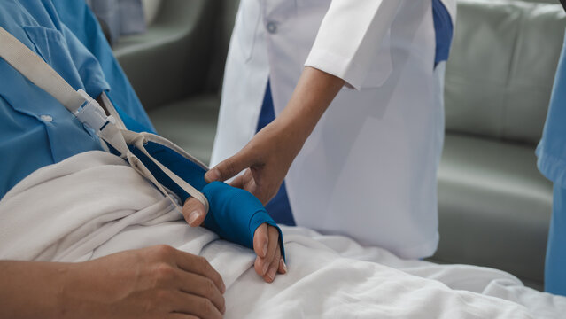 The medical team visits the car accident patients who are lying on the nursing bed and arm cast with wrapping nurse bandages splint to the arm.