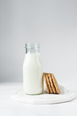 Oat cookies next to milk bottle, homemade oatmeal cookies, thin oat biscuits and milk