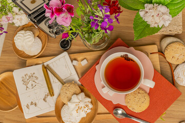 cup of tea with cookies, photo album, and notebook