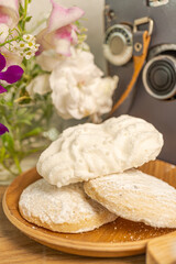Obraz na płótnie Canvas White cookies and meringue with flowers and film camera