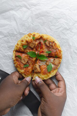 Hands pulling an individual pizza apart, homemade mini pizza, pizza with sausage, basil and cheese