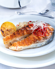 Healthy lunch bowl with grilled salmon, quinoa, and vegetables. Delicious salmon steak on table served with quinoa.