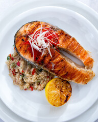 Healthy lunch bowl with grilled salmon, quinoa, and vegetables. Delicious salmon steak on table served with quinoa.