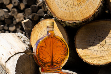 A bottle of delicious maple syrup in hardwood forest setting. The bottle of syrup near the maple...