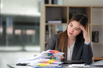 Sad Asian woman looking annoyed and stressed, sitting at the desk, using a laptop, thinking, feeling tired and bored with depression problems