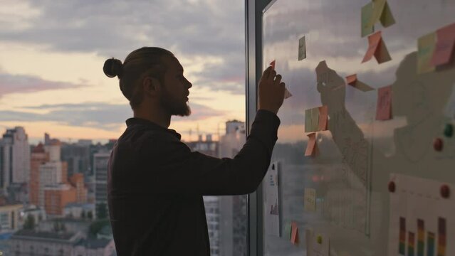 Man silhouette attaching stickers sunset office closeup. Two people taking break