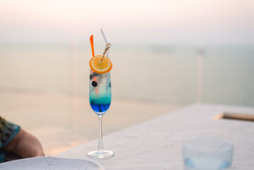 Woman drinking flavored cocktails on a rooftop with beautiful sunset