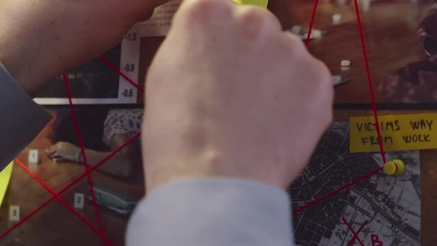 Detective's hands place yellow sticky note on evidence board