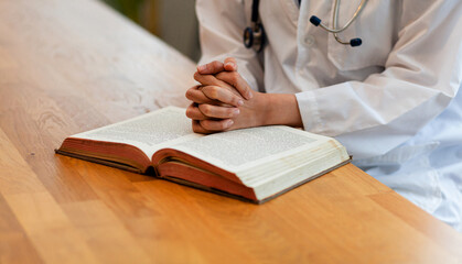 Coronavirus disease Covid-19. Female doctor or nurse prays with hands together in a gesture of hope...