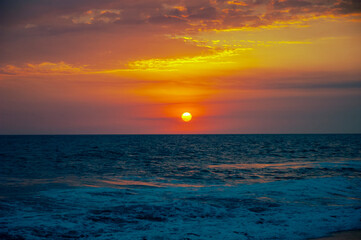 Sunset on black sand beach in Guatemala, tropical sunset full of color and waves.