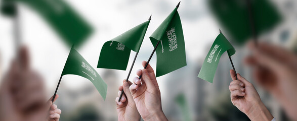 A group of people holding small flags of the Saudi Arabia in their hands