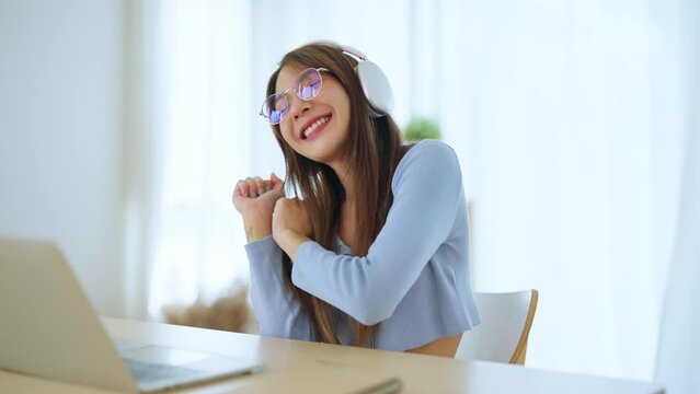 Happy young asian woman relaxing at home. Smiley female working on computer laptop. Girl using video call to friend, Wearing headset listening to music