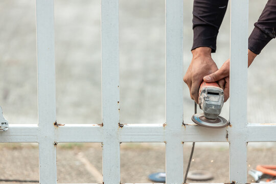 Tradesman Uses An Electric Grinder To Attrition On The Iron Door.