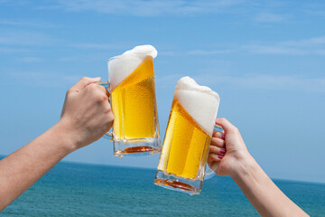 青空と海の前でビールで乾杯