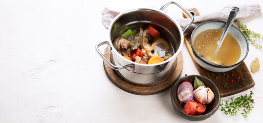 Pot of soup with beef and fresh vegetables on a white background.