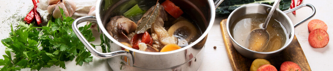 Pot of soup with beef and fresh vegetables on a white background.