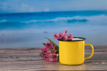 Flower ornament with yellow cup on table with fond beach, vacation concept.
