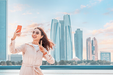 Embodying the spirit of modernity and progress in the UAE's capital city, a girl snaps a selfie against the dazzling skyline of Abu Dhabi.