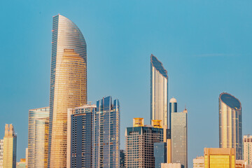 Naklejka premium Marvel at the breathtaking beauty of Abu Dhabi's towering buildings at sunset, iconic skyline that's recognized around the world.