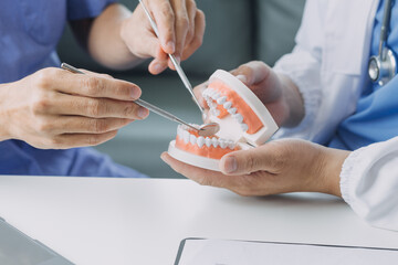 Dentists are discussing dental problems at report x-ray image on laptop screen to patients..