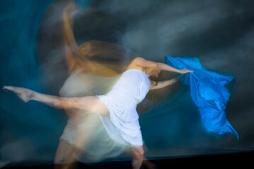 Mystical, blurry dance photo of adult woman with floating blue fabric.