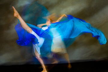 Mystical, blurry dance photo of adult woman with floating blue fabric.