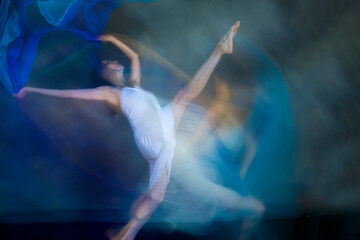 Mystical, blurry dance photo of adult woman with floating blue fabric.