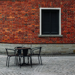 Empty black table and chair against a beautiful brick wall with a window covered with shutters