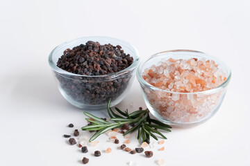 Top view of variety of different flake flower sea salt, Himalayan black salt and pink Himalayan with rosemary for cooking or spa on white background.