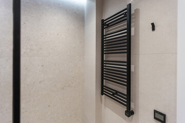 Modern and stylish black heated towel rail with thermostat. Metal heated towel rail on the wall of...