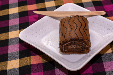 Chocolate Swiss Roll cake on a white plate.
