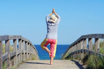 Fototapeta na wymiar Frau in Yoga Pose am Strandübergang
