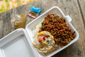 Stir fried Thai basil with minced pork and a fried egg on white plate