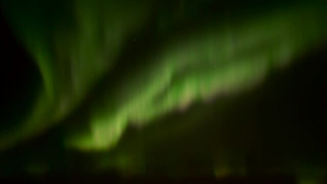 Realtime videos of the northern lights in green, pink and orange colours with a clear dark starry sky in the background 