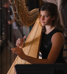 Close-up view of young adult female playing harp indoors