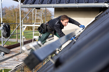 Craftsman installing solar panel support structures on the roof of a German single-family home